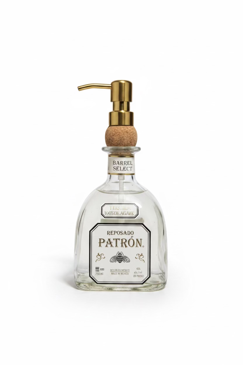 A clear glass soap dispenser with a gold-colored metal pump, labeled 'Reposado Patron'.