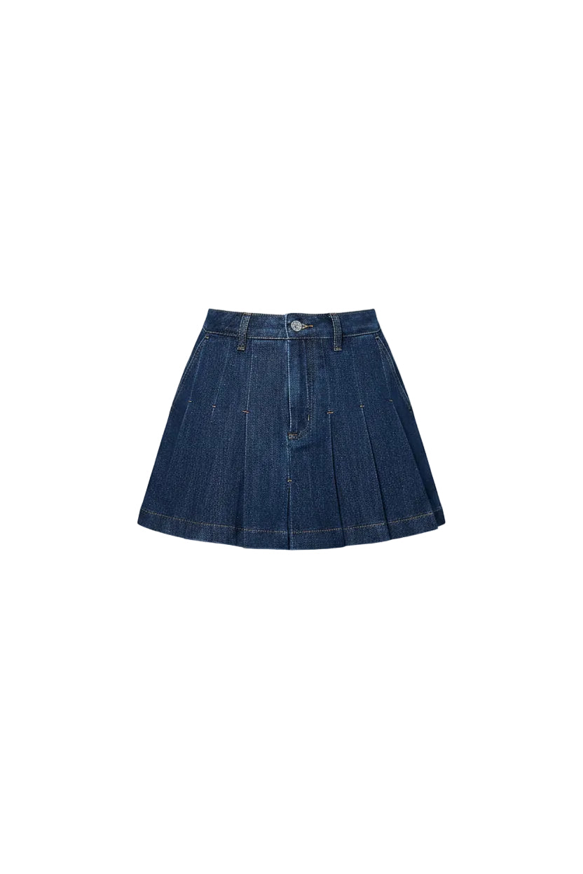 Person wearing a blue denim skirt and black cowboy boots against a light blue wall.