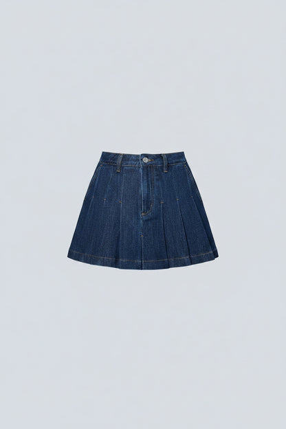 Person wearing a blue denim skirt and black cowboy boots against a light blue wall.
