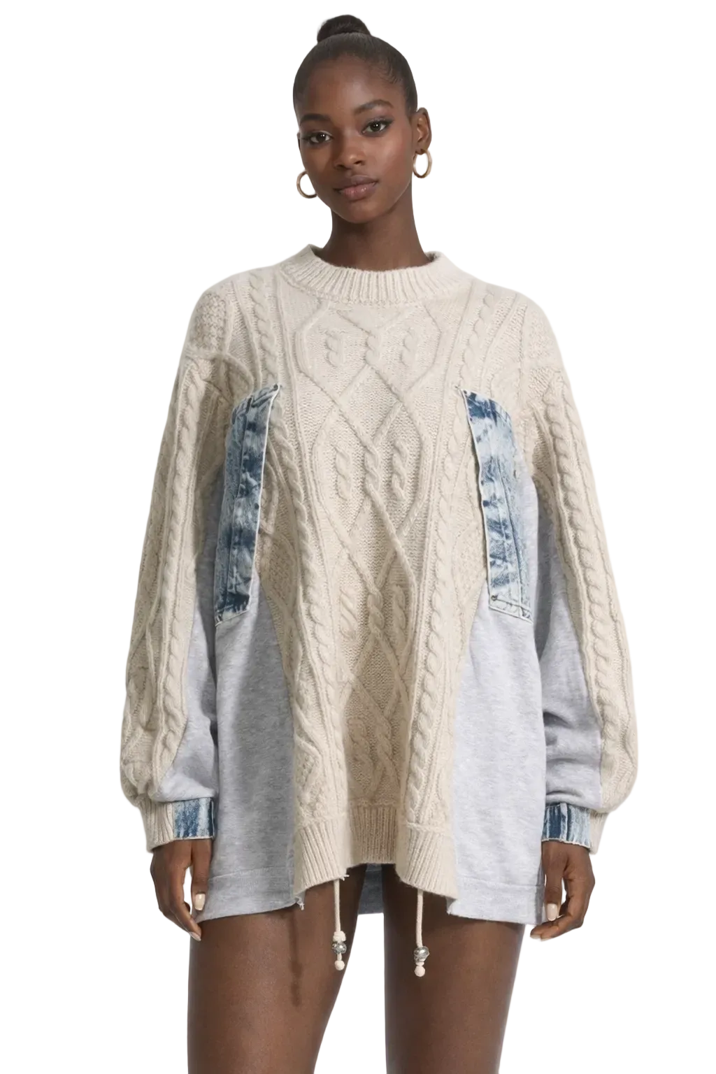 A model wearing an oversized cream cable-knit sweater with light blue denim patch pockets and a light gray knit undershirt, shown against a plain white background.