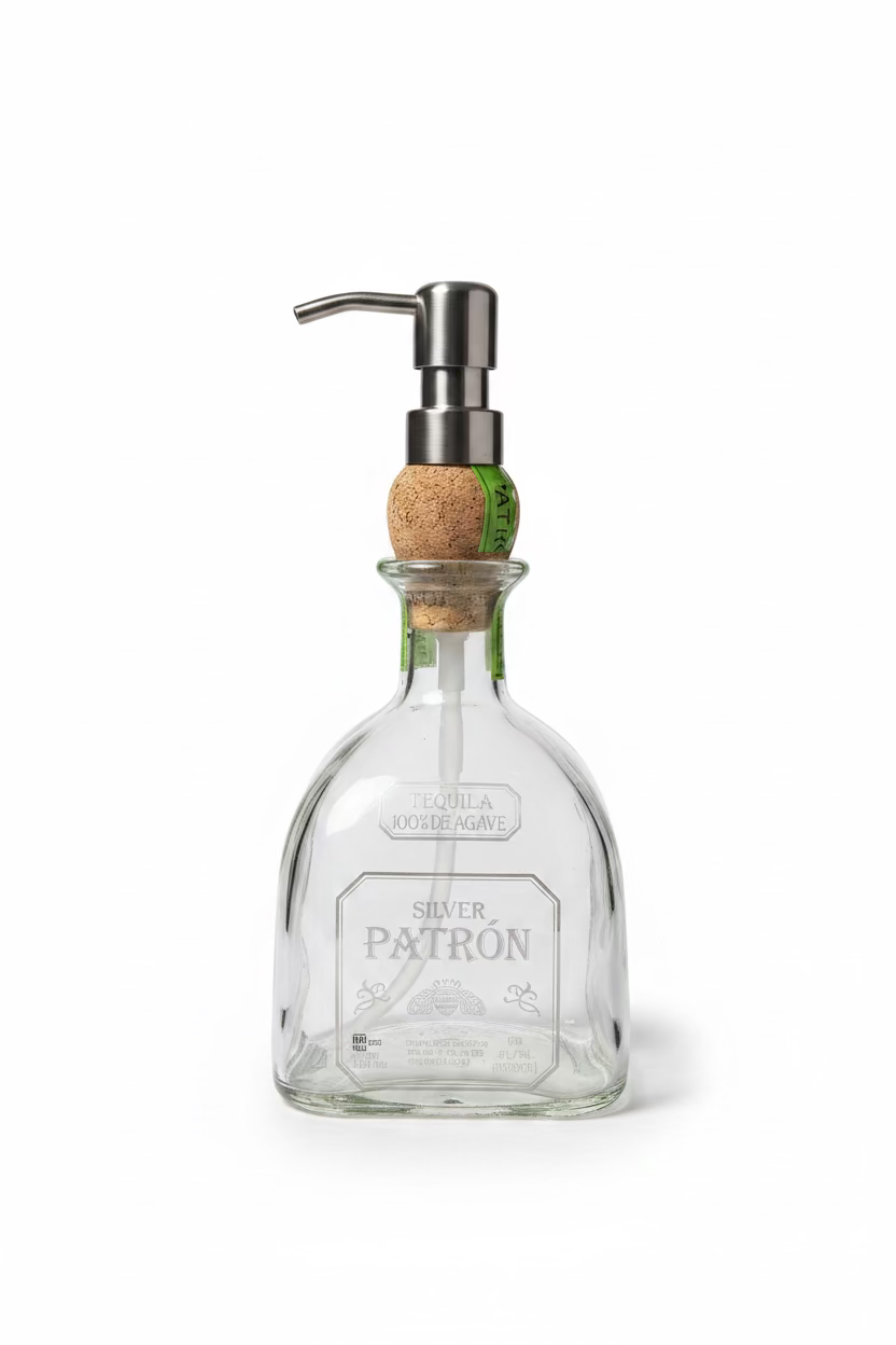 A clear glass soap dispenser with a metal pump and a cork stopper