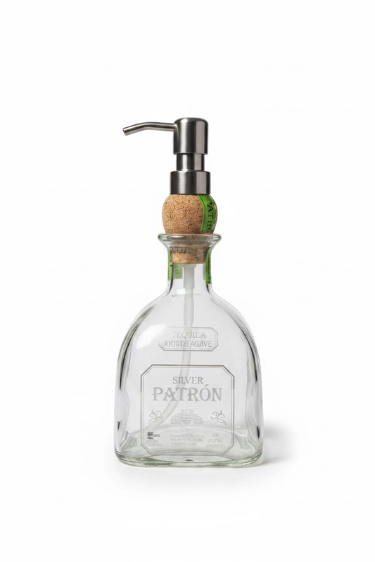 A clear glass soap dispenser with a metal pump and a cork stopper