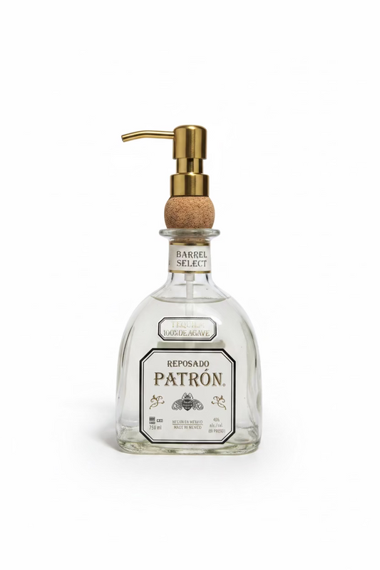 A clear glass soap dispenser with a gold-colored metal pump, labeled 'Reposado Patron'.